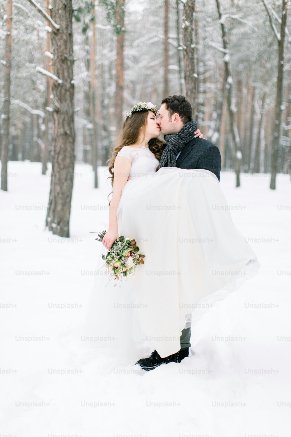 Winter wedding couple, bride and groom at their winter wedding day. Handsome groom holds her bride on hands.