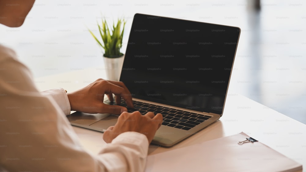 Cropped shot of Businessman using black blank screen laptop on work desk.