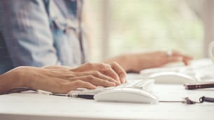 Close up shot of businesswoman hand typing and working on desktop computer on the office desk. Business communication and workplace concept.