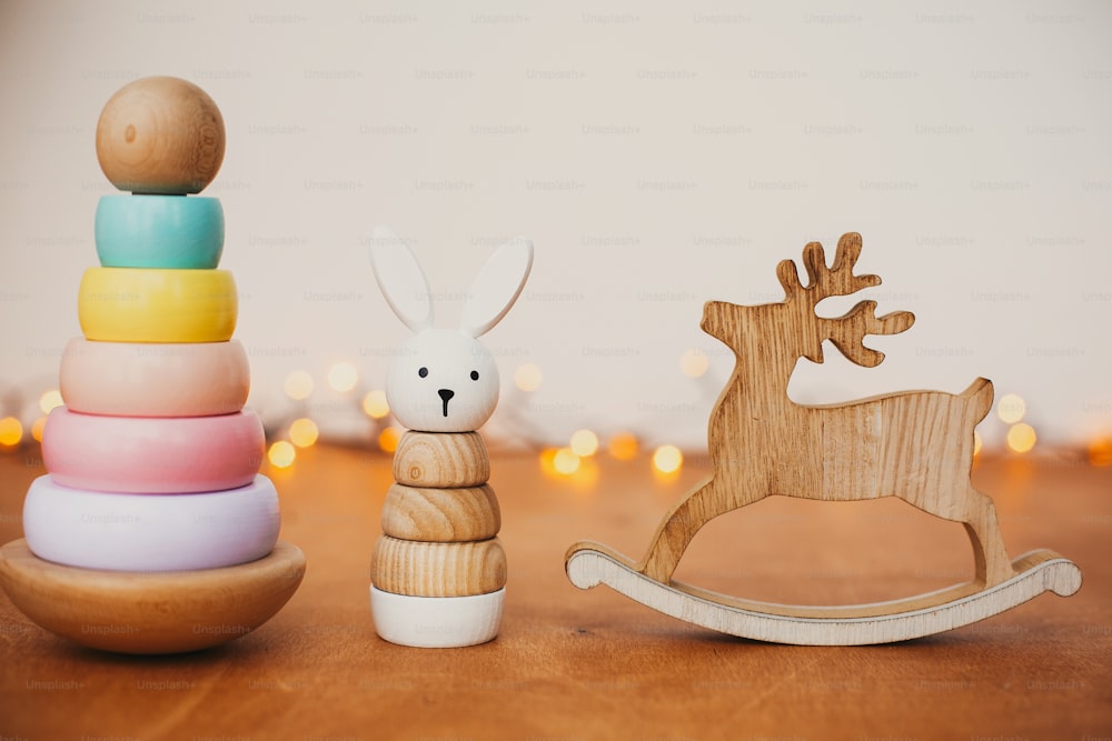 Stilvolles Holzspielzeug für Kinder auf Holztisch. Moderne bunte Holzpyramide mit Ringen, einfachem Hasen und Rentier. Umweltfreundliches plastikfreies Lernspielzeug für Kleinkinder