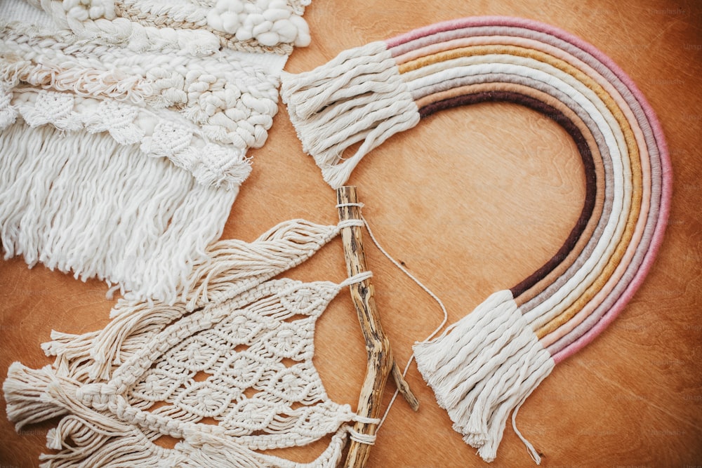 Stylish macrame and rainbow decoration on wooden table. Modern boho wall hanging and rope rainbow for baby room or simple stylish girl room. Wall macrame decor