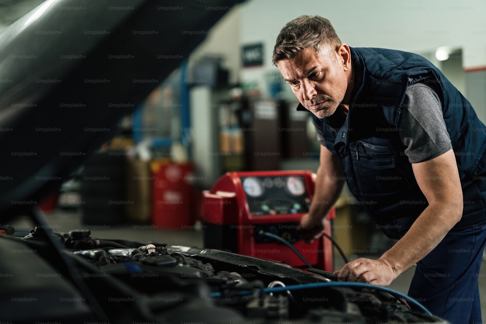 修理工場で車の空調システムをメンテナンスする自動車整備士。