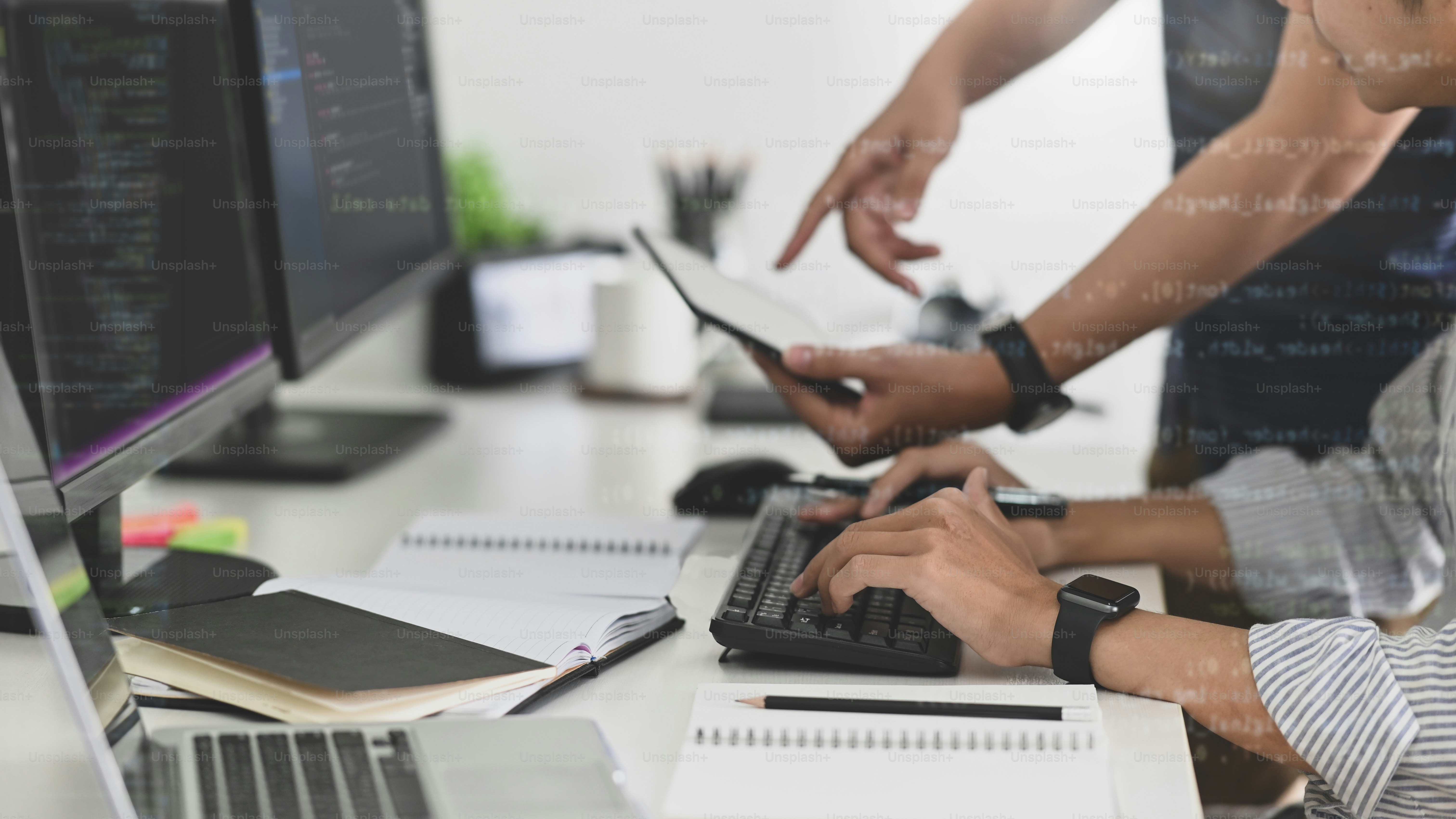 Tim muda programmer pria menulis kode program dan diskusi di tempat kerja dengan perangkat komputer.