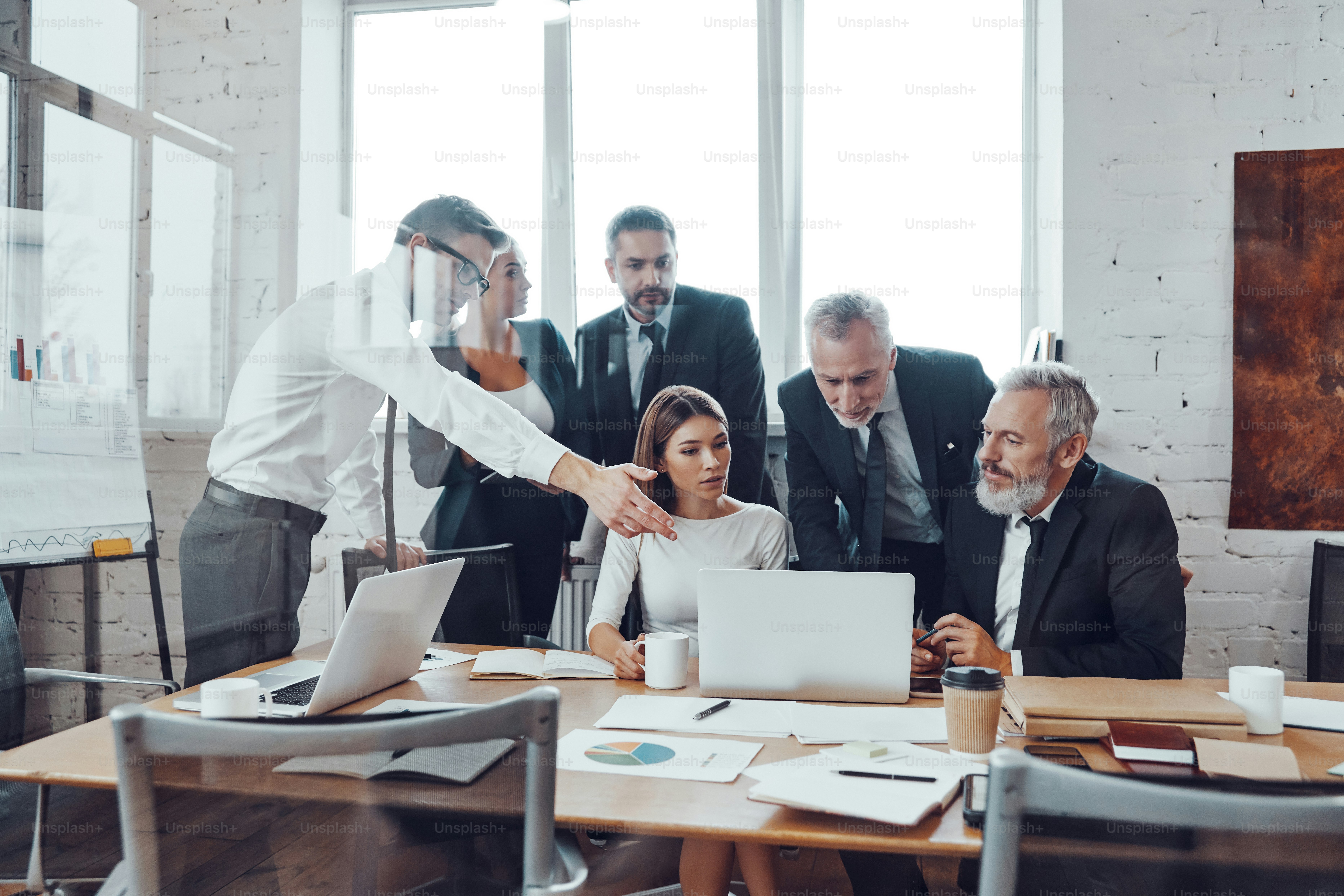 Professional business team analyzing sales using modern technologies while having staff meeting in the board room
