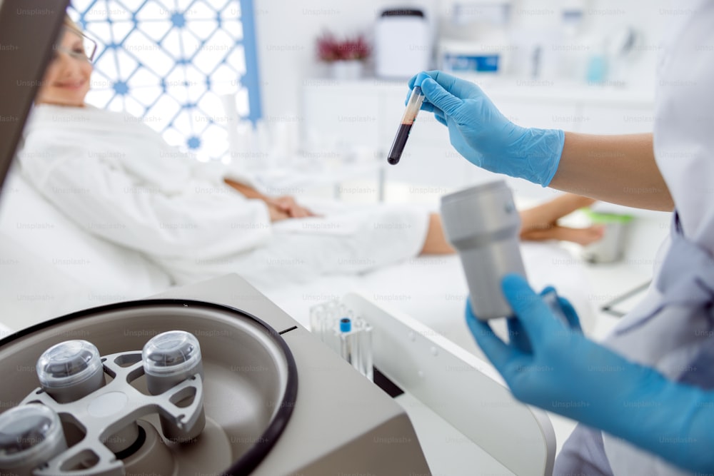 Medizinische Kosmetikerin, die das Blut in einem Reagenzglas in einer Zentrifuge gibt