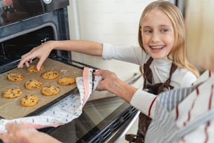 Woman taking out the baking tray with chocolate chip cookies