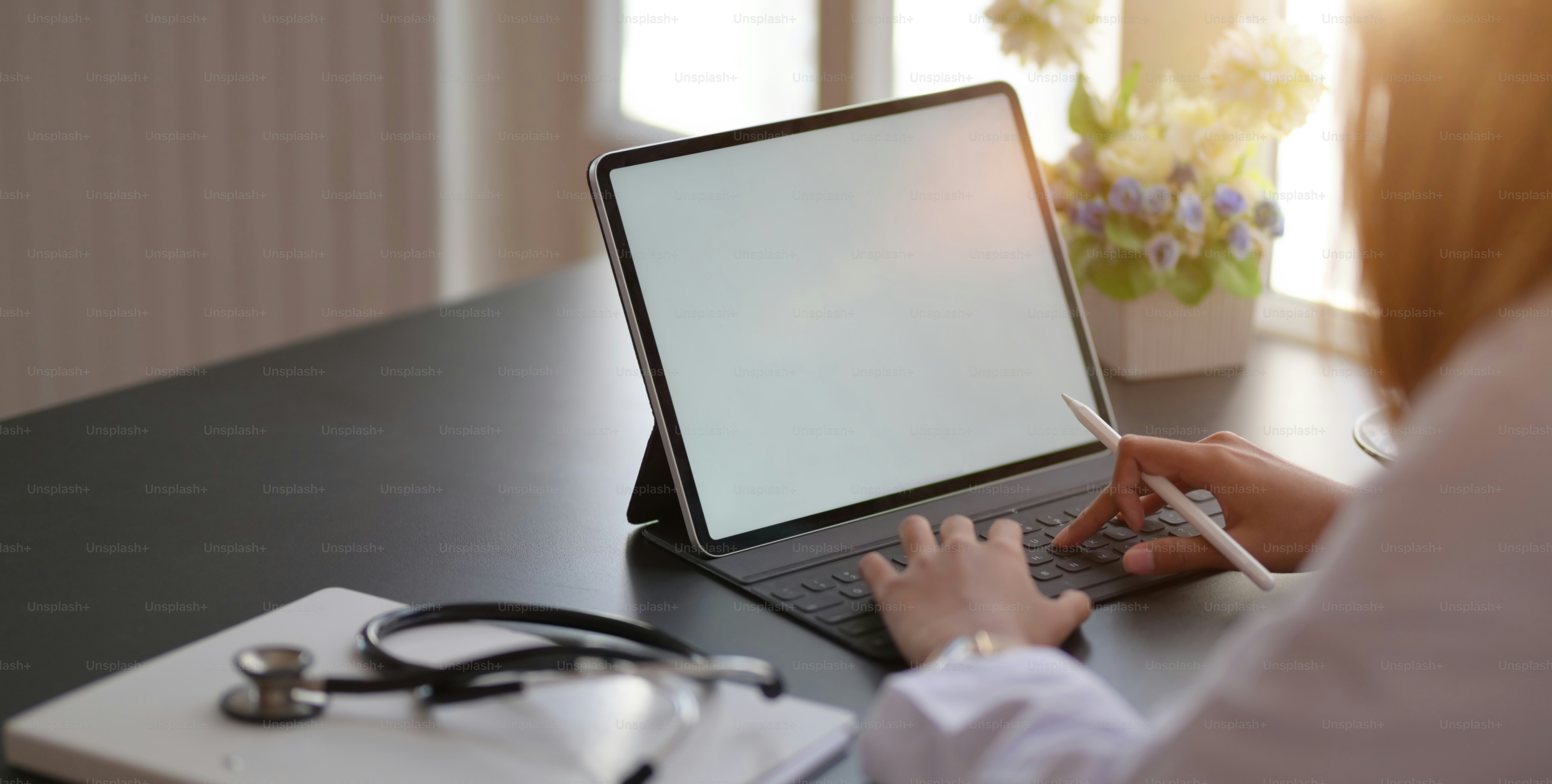 Cropped shot fo young female doctor working on medical records and exam results with tablet in hospital office