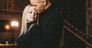 Portrait of a lovely young couple embracing while man is embracing her girlfriend from back indoor.