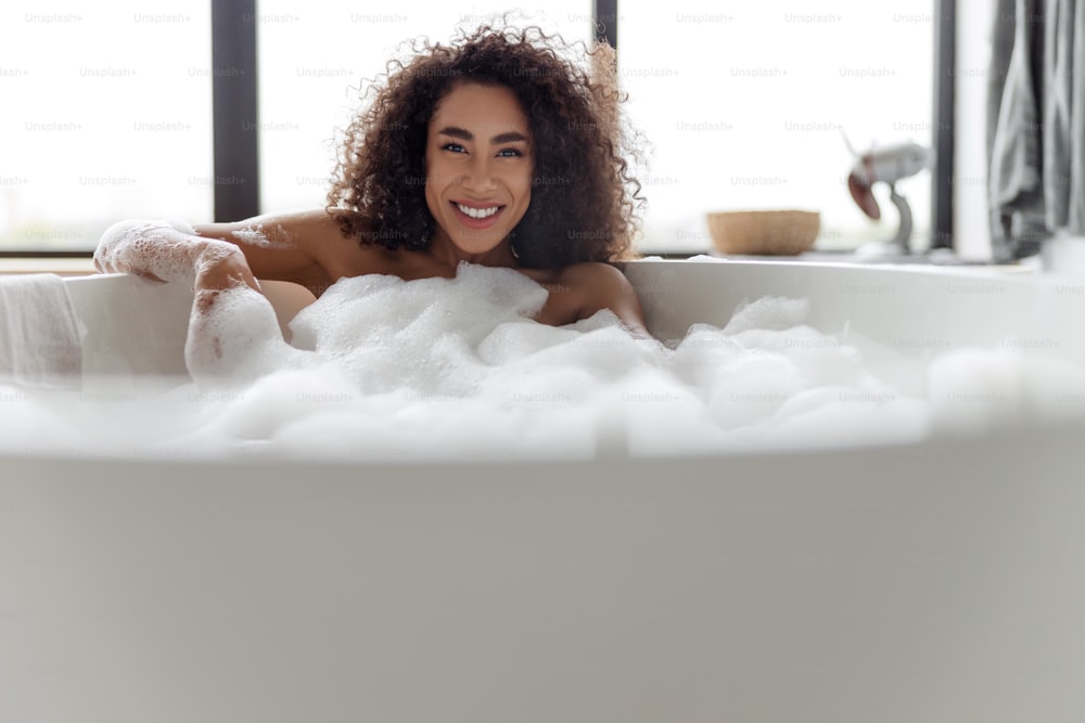 Smiling young woman relaxing in bathtub stock photo