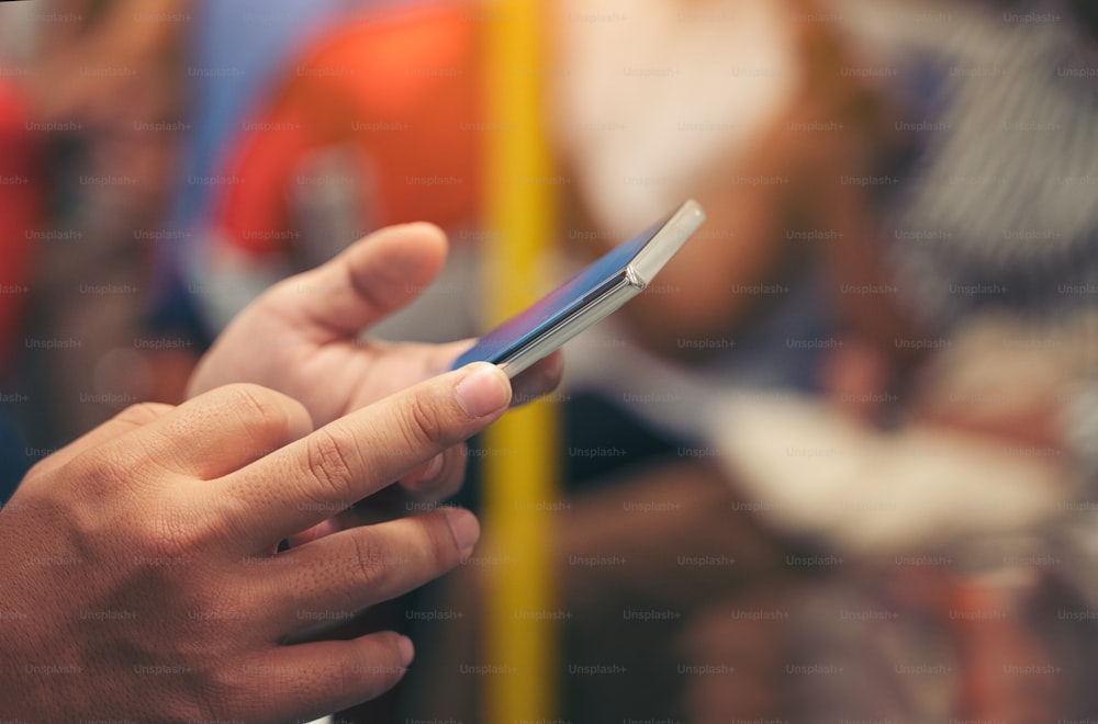 Imagen de primer plano de manos masculinas usando teléfono inteligente por la noche en el tren de la ciudad, buscando o concepto de redes sociales, hombre hipster escribiendo un mensaje sms a sus amigos
