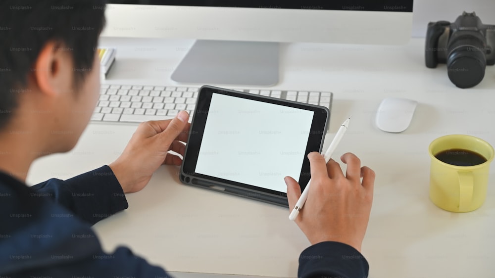 Creative man using mockup digital tablet on workspace.