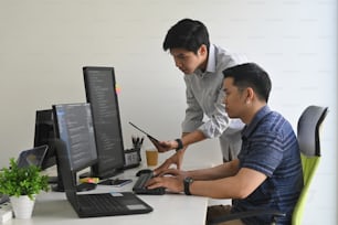 Young programmers working on computer and tablet in modern office workplace.