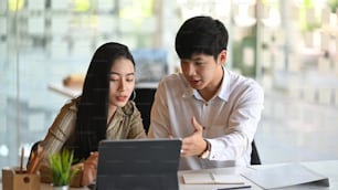 Asiatische Geschäftsleute, die sie mit digitalen Tablets im modernen Büro treffen.