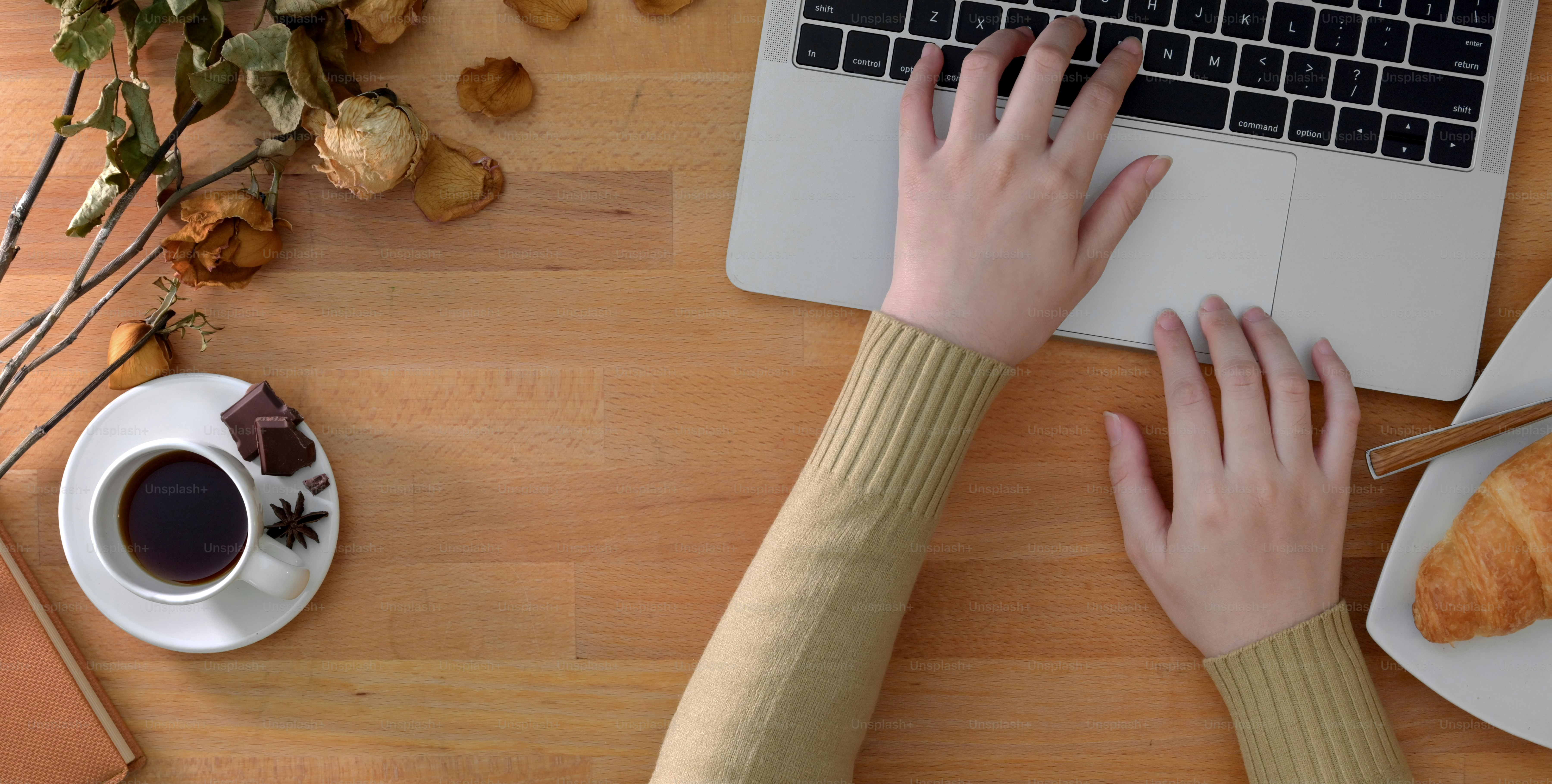 Vue de dessus d’une jeune femme tapant sur un ordinateur portable dans un lieu de travail confortable avec des fournitures de bureau sur une table en bois
