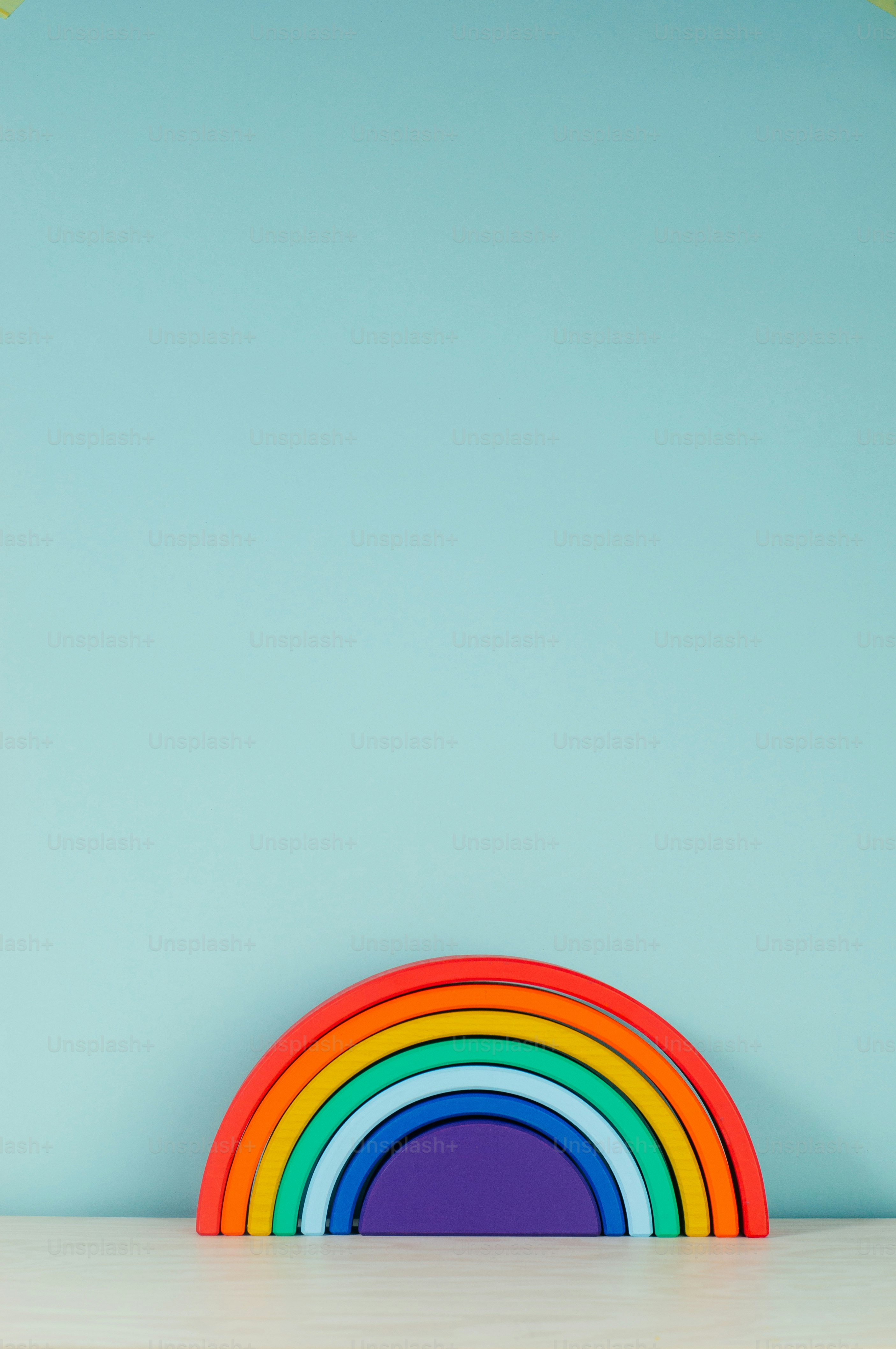 Wooden toy rainbow on the shelf in the kids room on blue background with blank text for text.