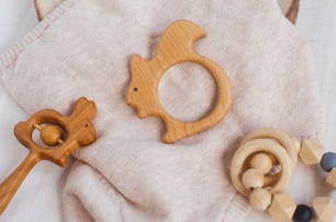 Wooden organic baby teether toys rabbit and squirrel on knitted material background. Top view, flat lay.