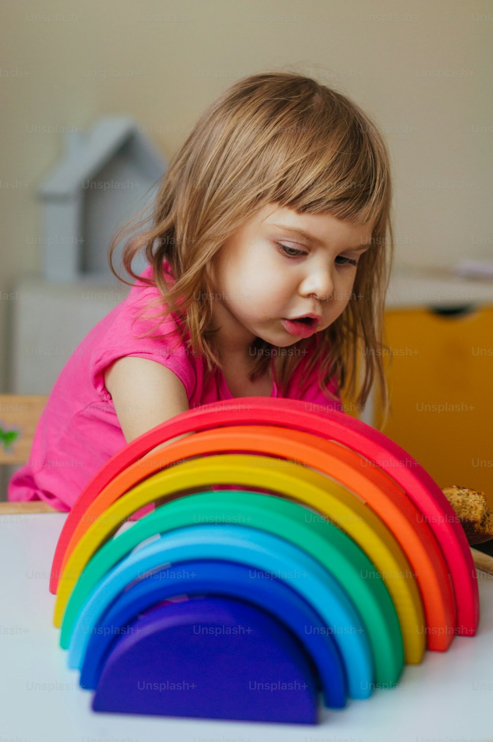 Nicht-Plastik-Holzspielzeug-Konzept. Schönes kleines Mädchen spielt mit buntem Holzspielzeugregenbogen im Kinderzimmer