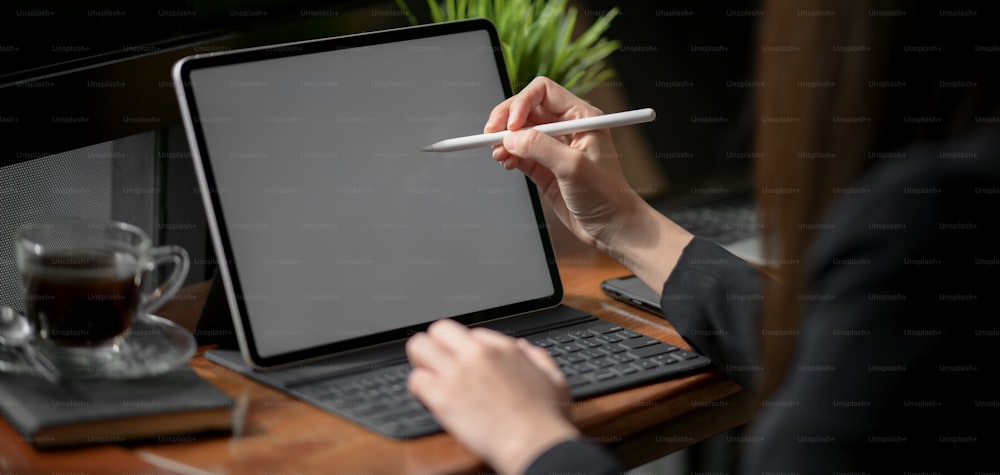 Close-up view of young professional businesswoman planing her strategy while using blank screen tablet