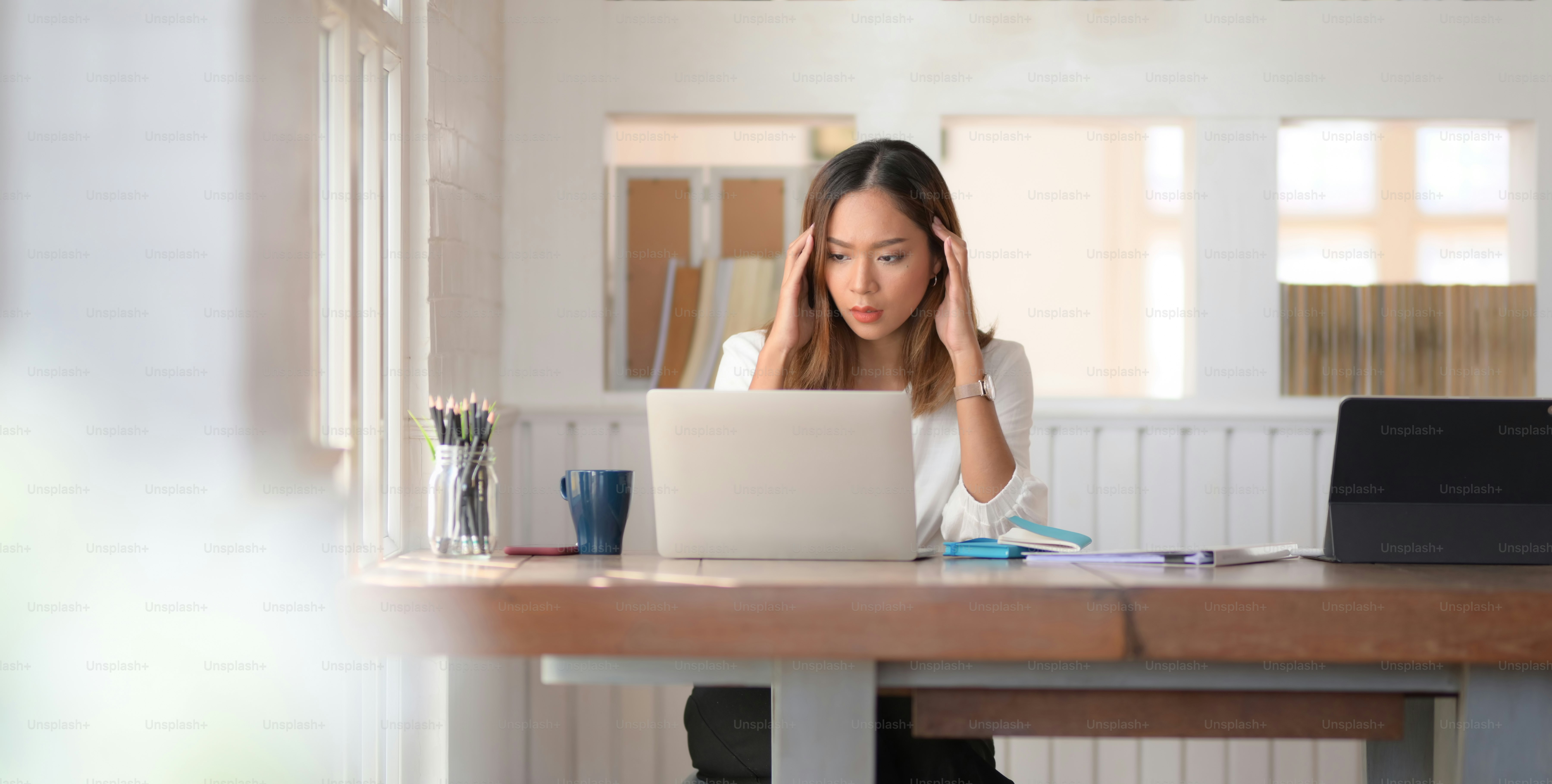 Tired beautiful Asian business woman working with headache in modern office room