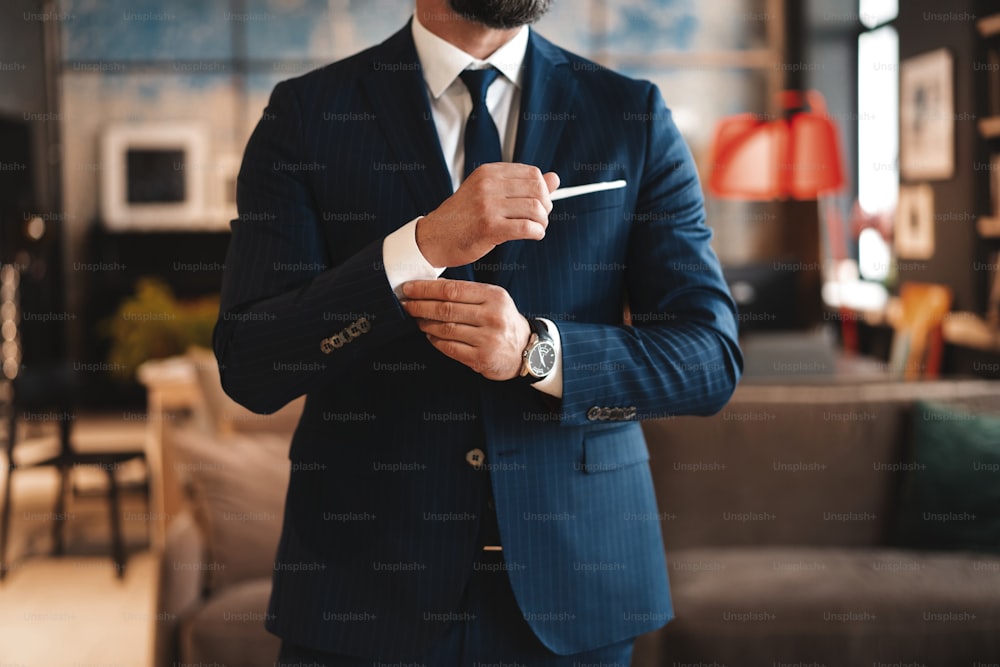 Perfect to the last detail. Handsome businessman adjusting his sleeves while standing in modern office