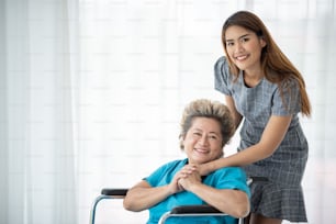 Asian daughter or care assistant helping support senior woman or mother