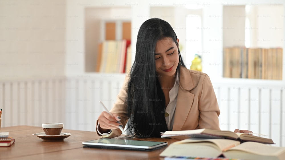 Editor female reading book with using tablet and stylus pen.