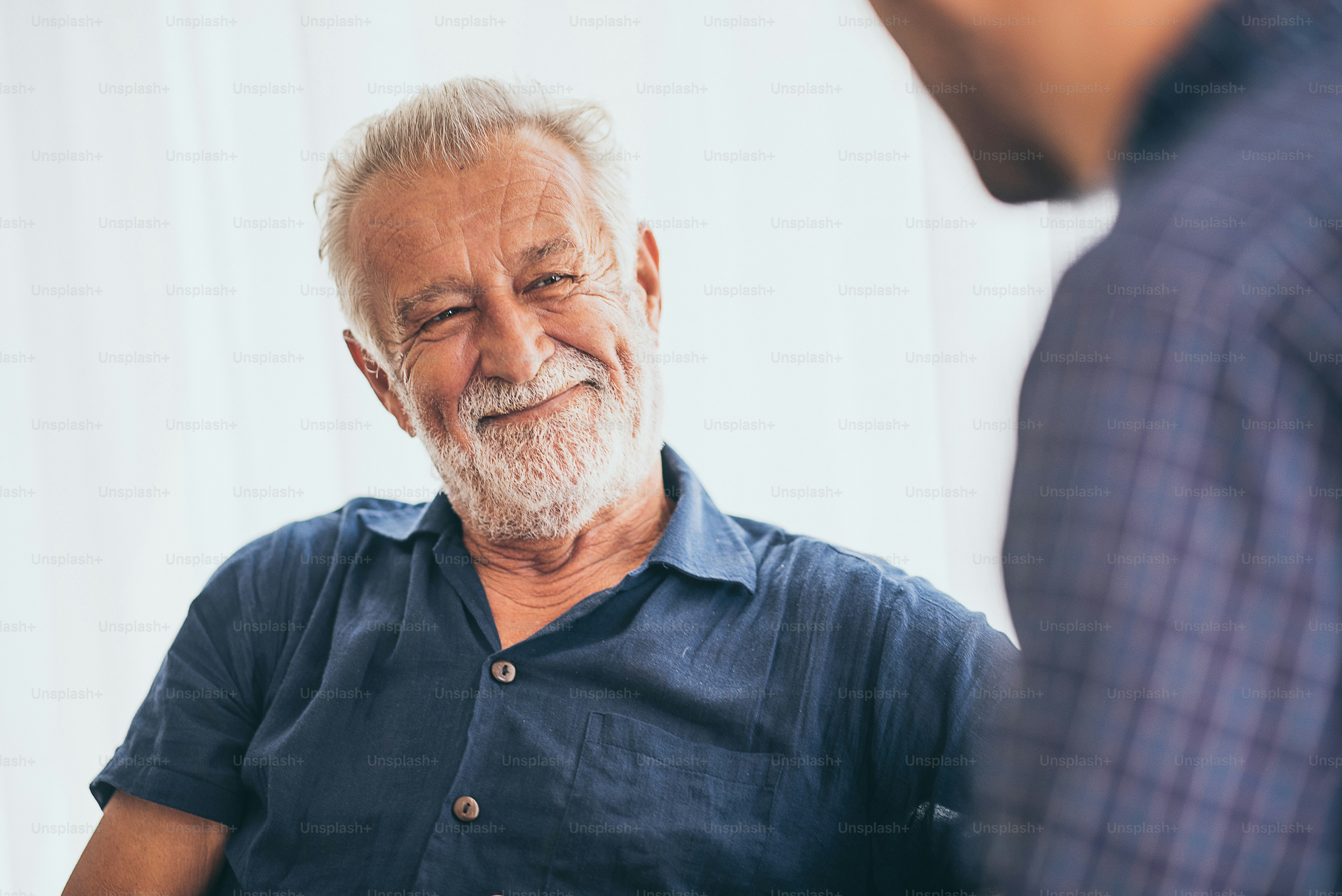 happy adult son and senior father laughing on sofa at home