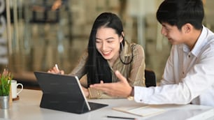 Asiatische Geschäftsleute, die sie mit digitalen Tablets im modernen Büro treffen.