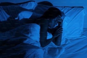 Young woman with a headache and insomnia in the dark bedroom