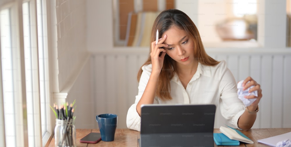 Tired beautiful asian business woman working with headache in modern office room