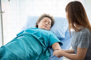 Arzt oder Krankenschwester hält die Hände einer älteren Dame.