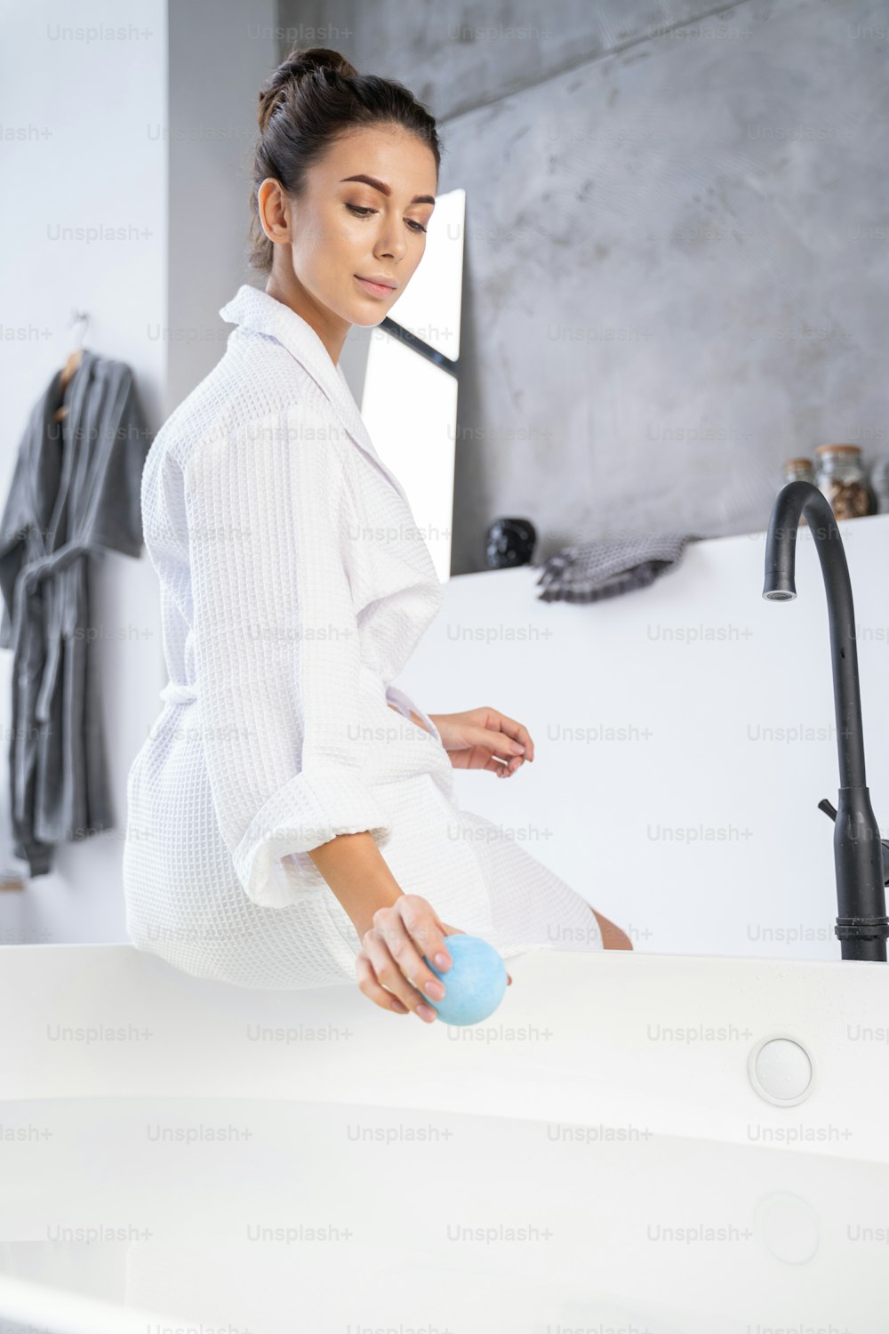 Young woman adding a bath bomb to the hot water