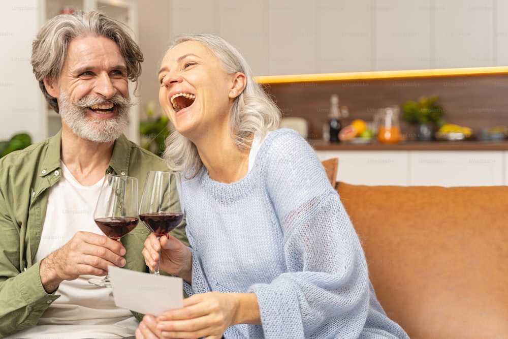 Gleeful Caucasian couple holding two glasses of red wine