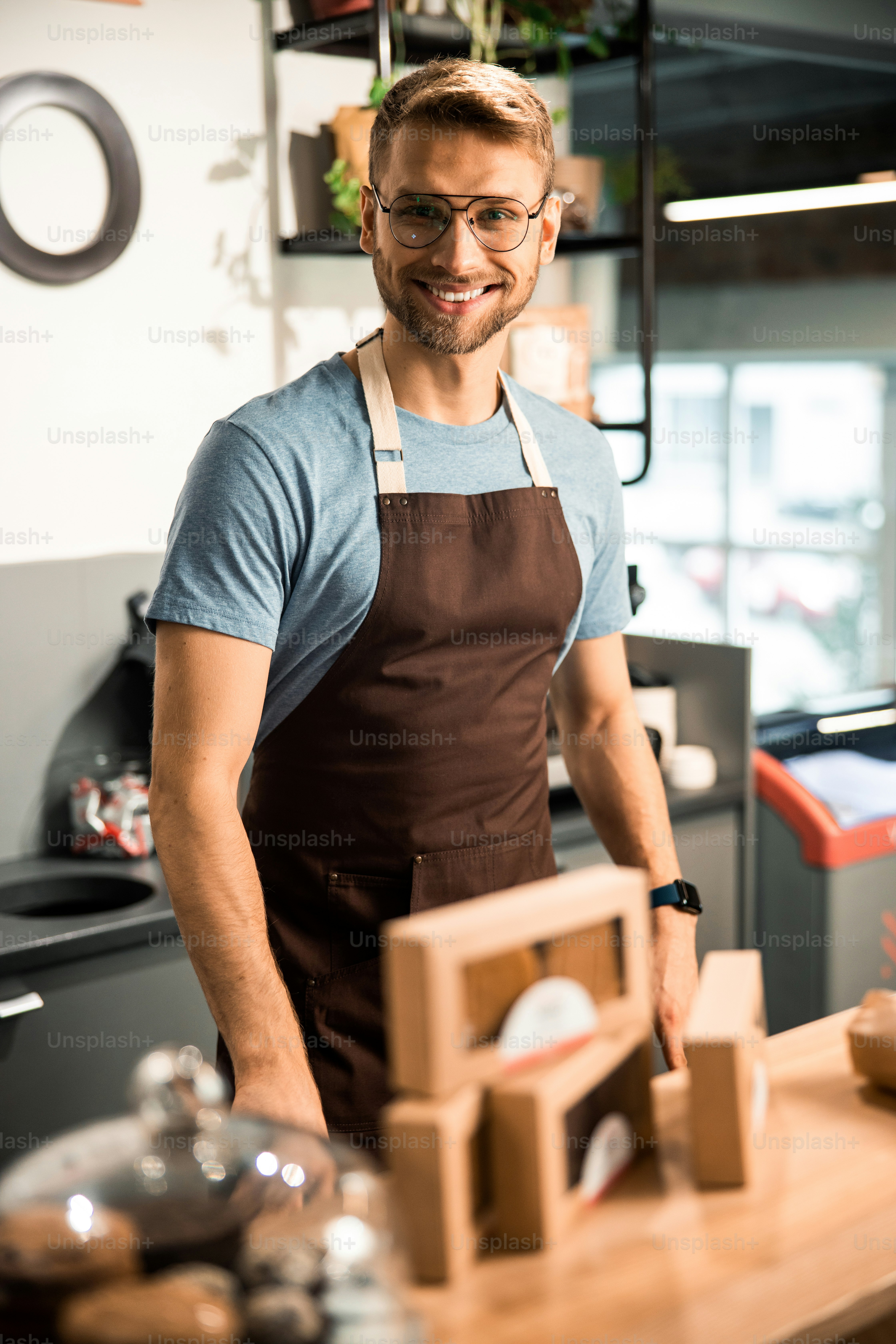 Shot of young barista posing near the showcase at his cafe stock photo