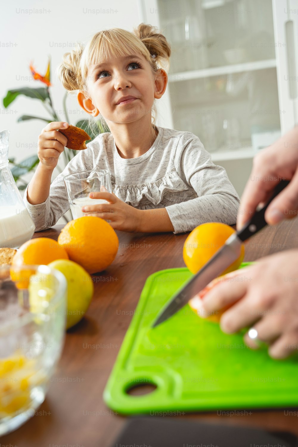 Adorable child having breakfast while her dad cutting orange stock photo
