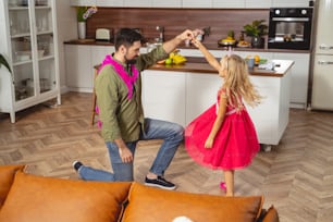 Adorable little girl in beautiful dress celebrating birthday with her dad at home stock photo