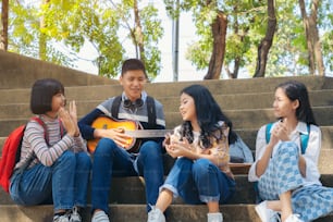 Group of child student playing guitar and singing songs together in summer park