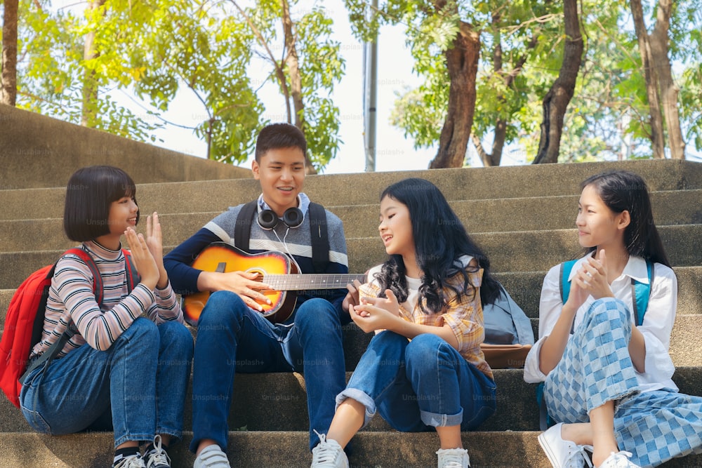 Group of child student playing guitar and singing songs together in summer park