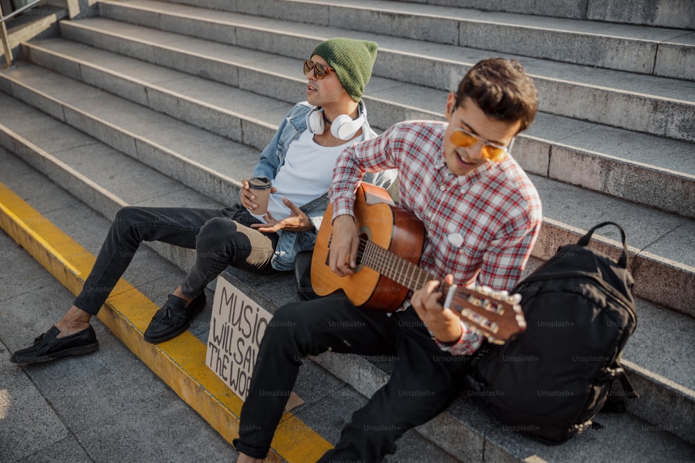 Two guys resting on steps while singing a song in the city stock photo