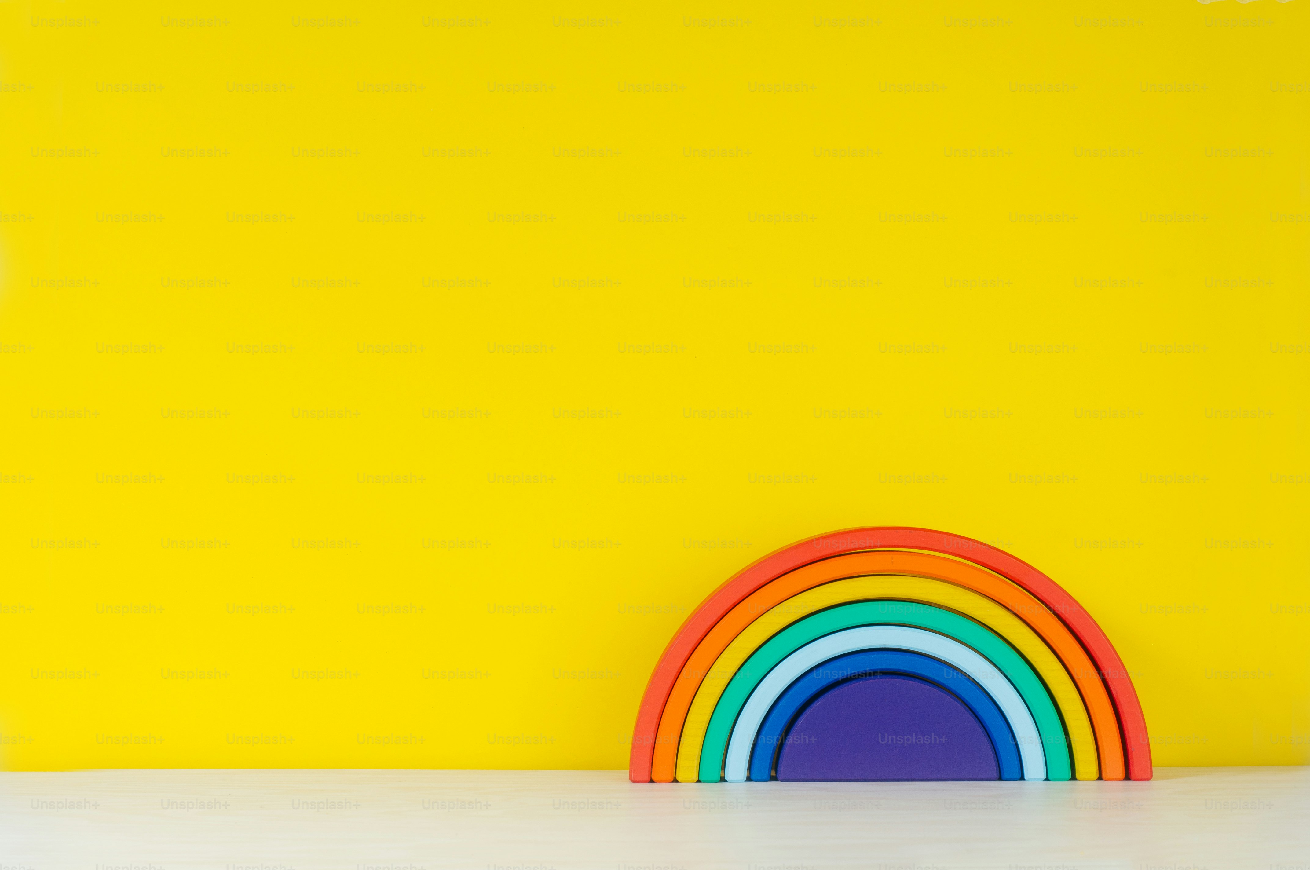 Wooden toy rainbow on the shelf on yellow background with blank text for text.
