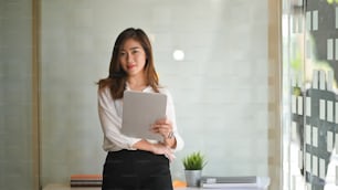 Portrait shot confident businesswoman standing in modern office and looking at camera.