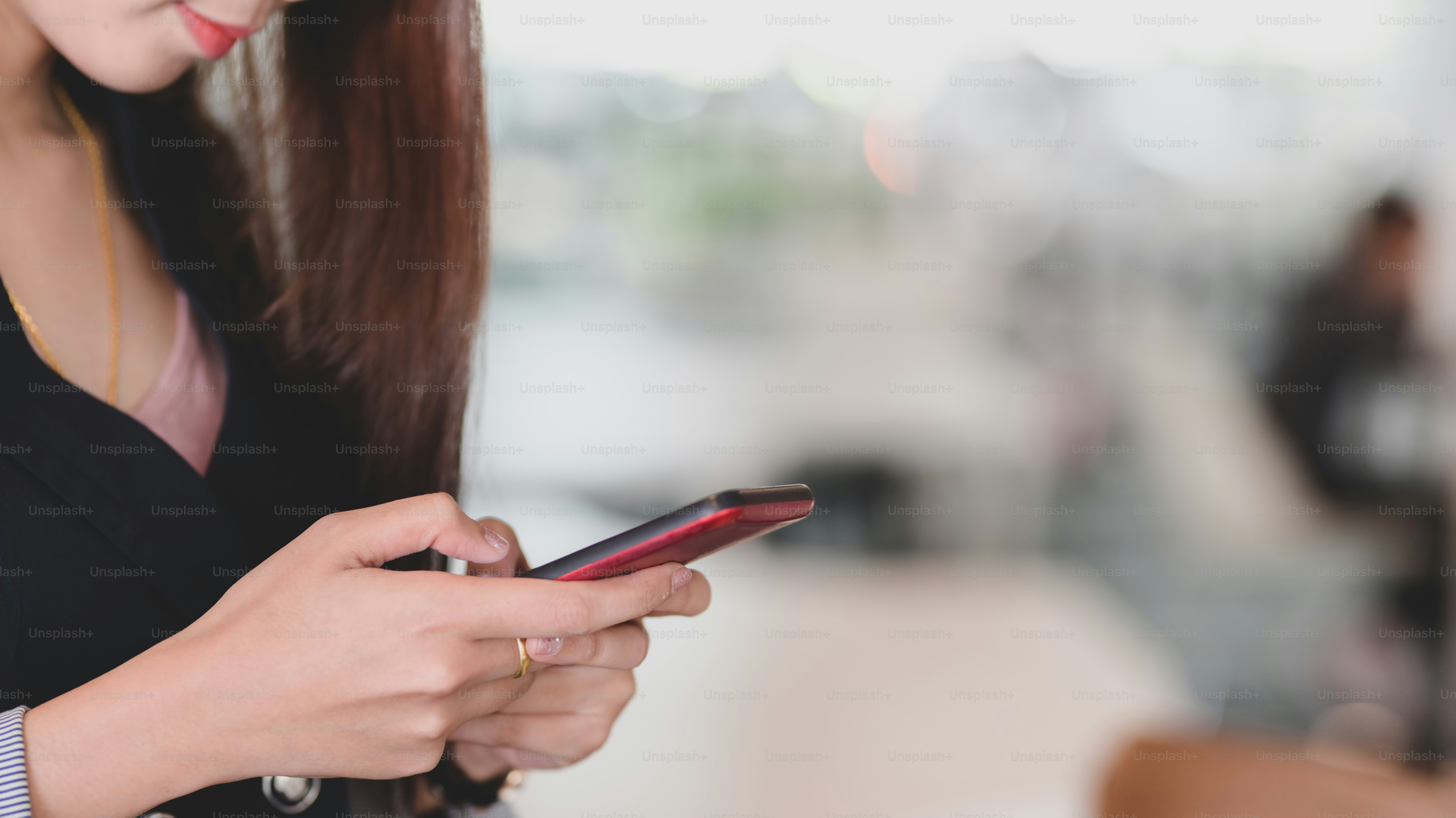 Vista de cerca de jóvenes empresarias profesionales que usan en un teléfono inteligente con fondo borroso de la sala de oficina
