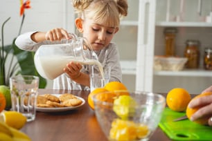 Entzückendes Kind sitzt am Küchentisch und hat ein Glas Milch am Morgen Stockfoto