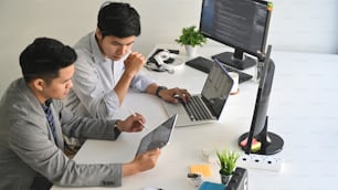 Deux programmeurs masculins travaillant avec un ordinateur portable et codant sur un ordinateur.