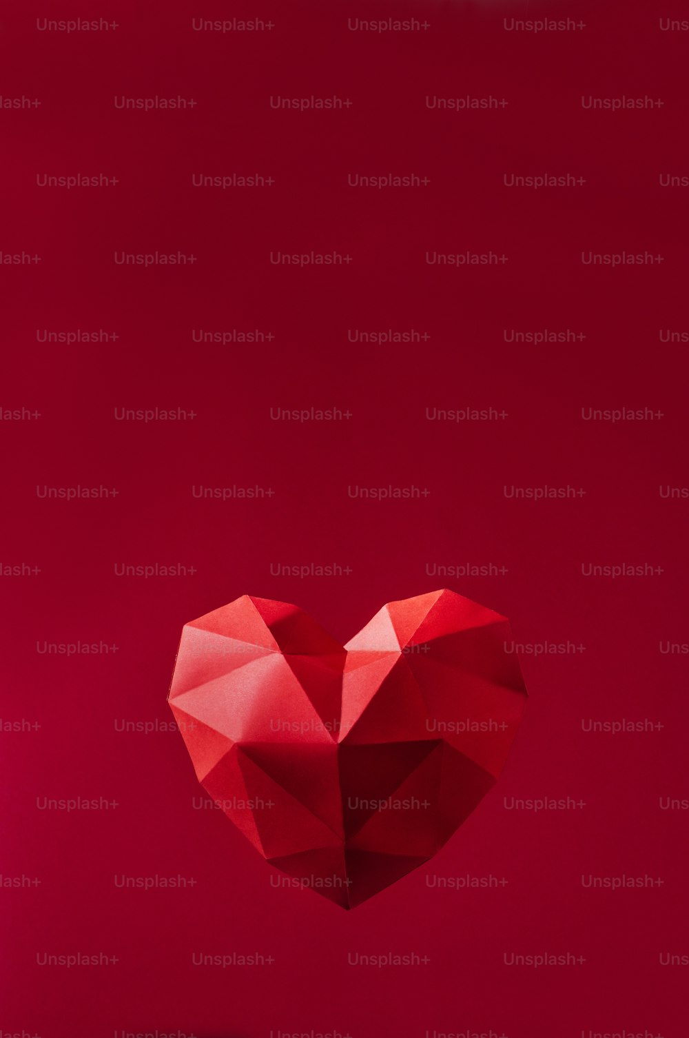 발렌타인 데이 배경 개념입니다. 빨간색 배경에 종이에 기하학적 볼륨 하트, 텍스트를 위한 빈 공간이 있습니다.
