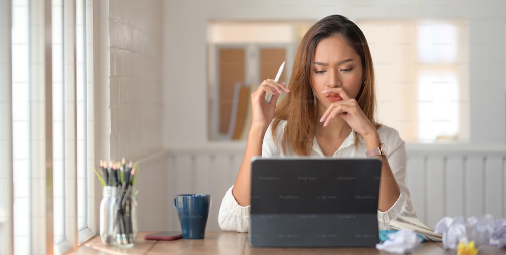 Young beautiful businesswoman concentrated in her work while using digital tablet in modern office room