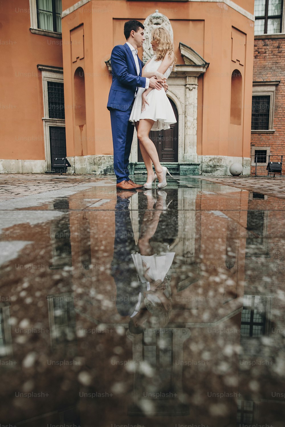 Couple élégant dansant dans la rue de la ville européenne sur fond d’architecture ancienne et de reflet dans l’eau. Homme et femme à la mode dans la danse amoureuse. Voyager ensemble en Europe