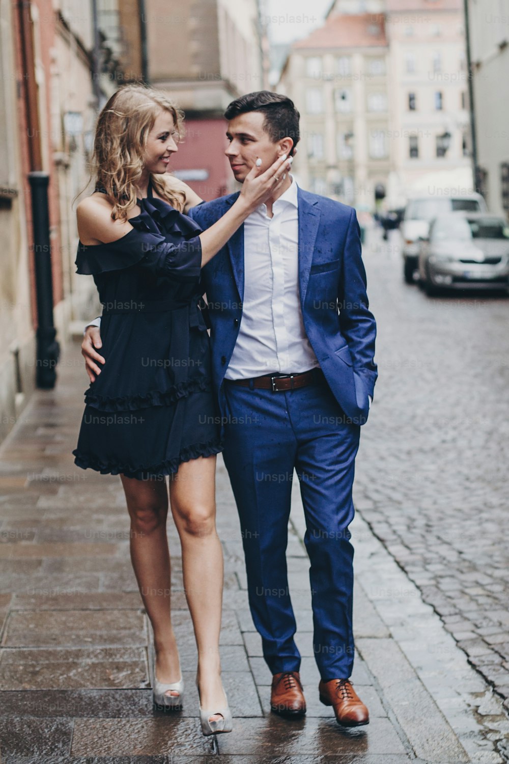 Stylish couple walking together in rainy european city street on background of old architecture. Fashionable man and woman in love enjoying day in city. Traveling together in Europe