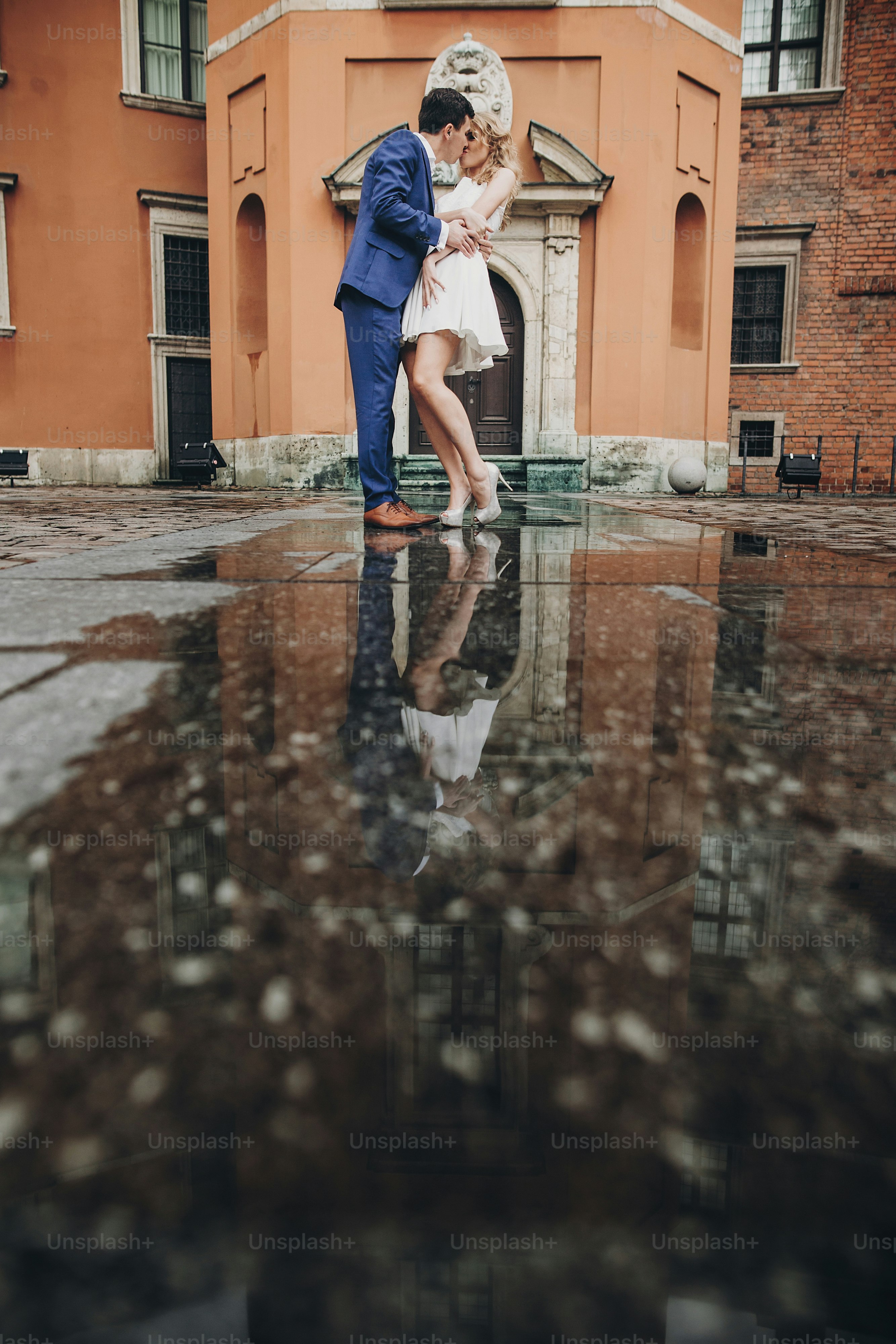 A man in a blue suit and a woman in a white dress kissing