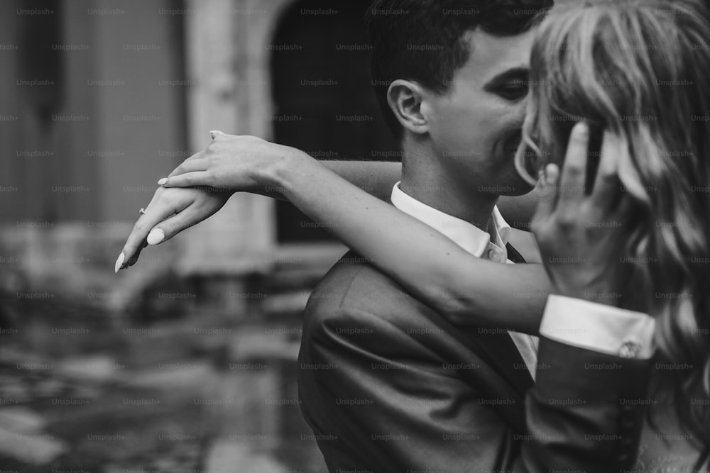 Stylish couple embracing in european city street. Sensual romantic  moment. Fashionable bride and groom in love gently hugging.Focus on hands. Valentines day